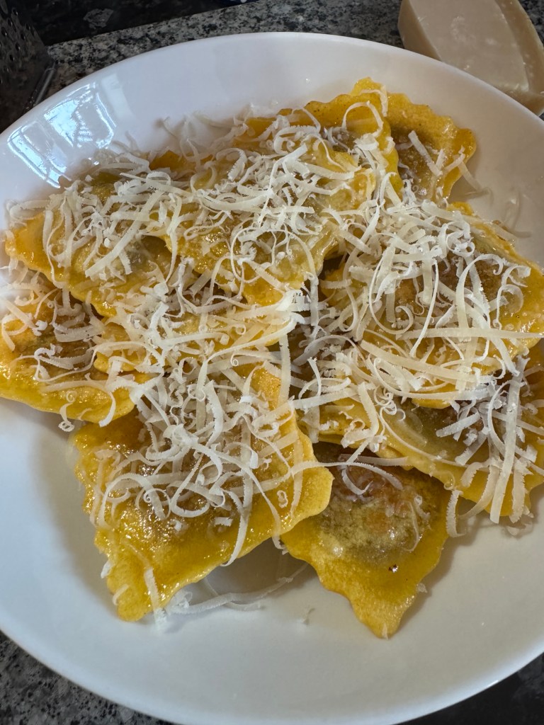 Pan-fried Wicked Kitchen gluten-free ravioli topped with grated cheese on a white plate